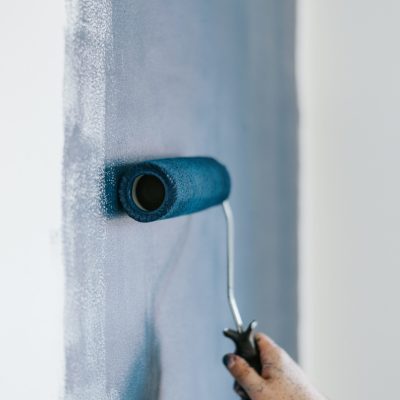 A closeup shot of a female using paint rollers with the color blue